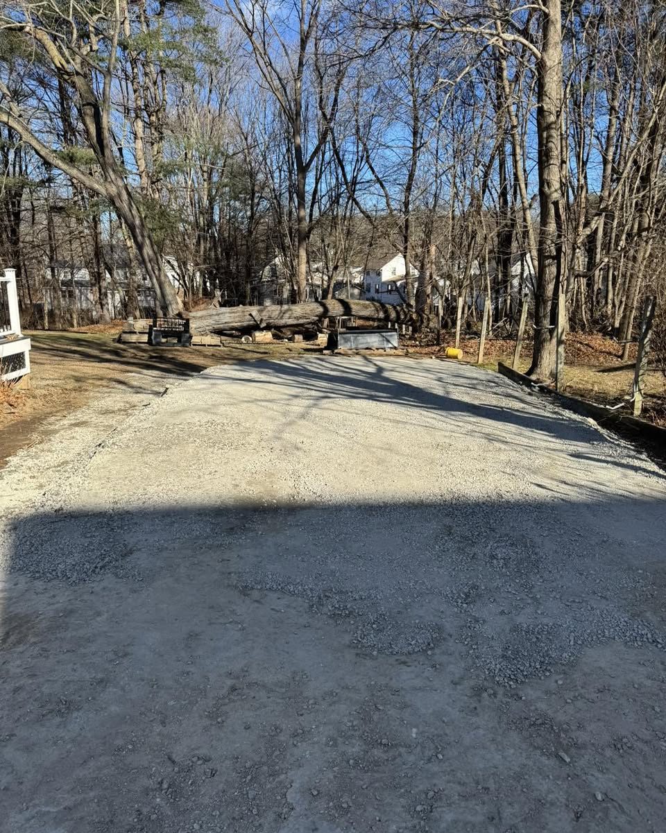 A newly installed crushed-gravel shed pad graded between the trees